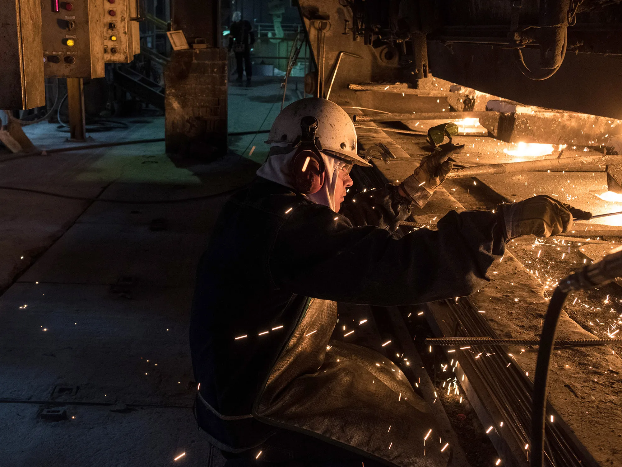 A worker oversees a machine converting liquid material into steel billets at a steel facility in San Luis Potosi, Mexico.