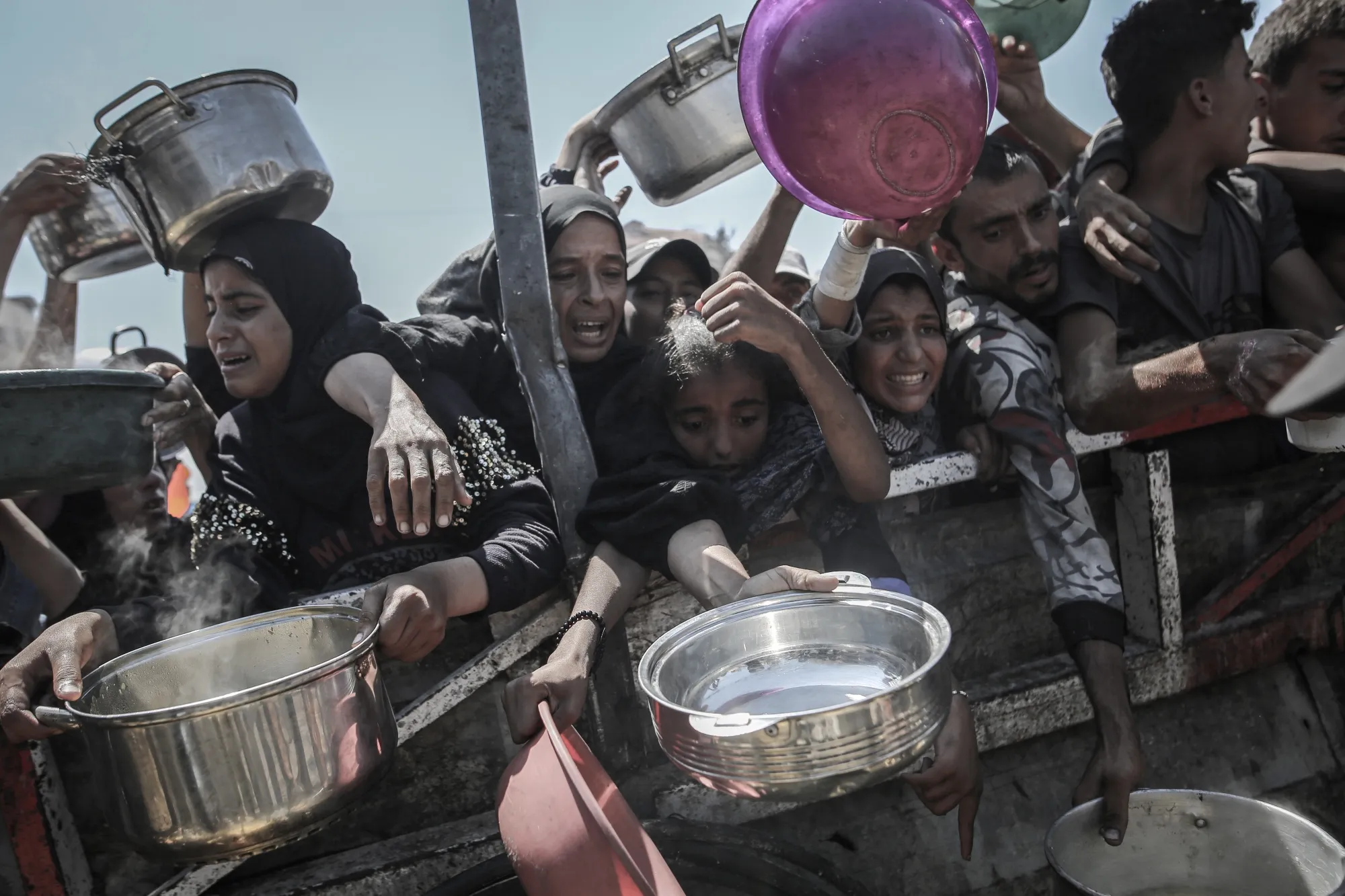 Palestinians try to collect free food from a charity kitchen in Gaza City.