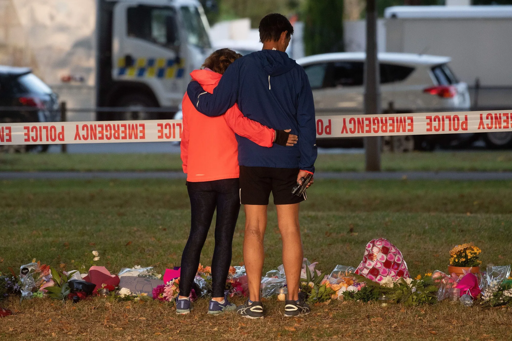People stand near tributes across the road from the Dean Avenue mosque in Christchurch on March 17