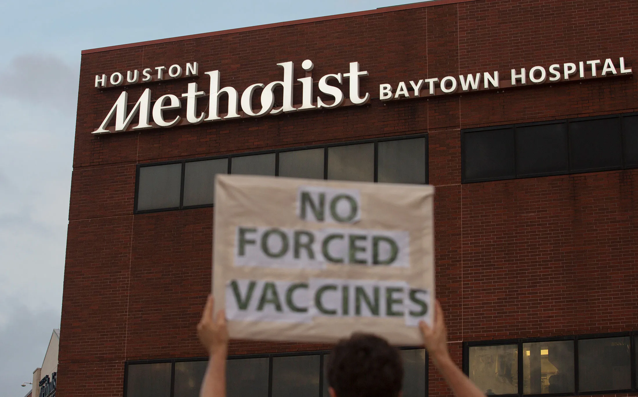 A person holds a sign in front of Houston Methodist in Baytown, Texas, to protest a policy that says hospital employees must get the Covid vaccine&nbsp;or lose their jobs.