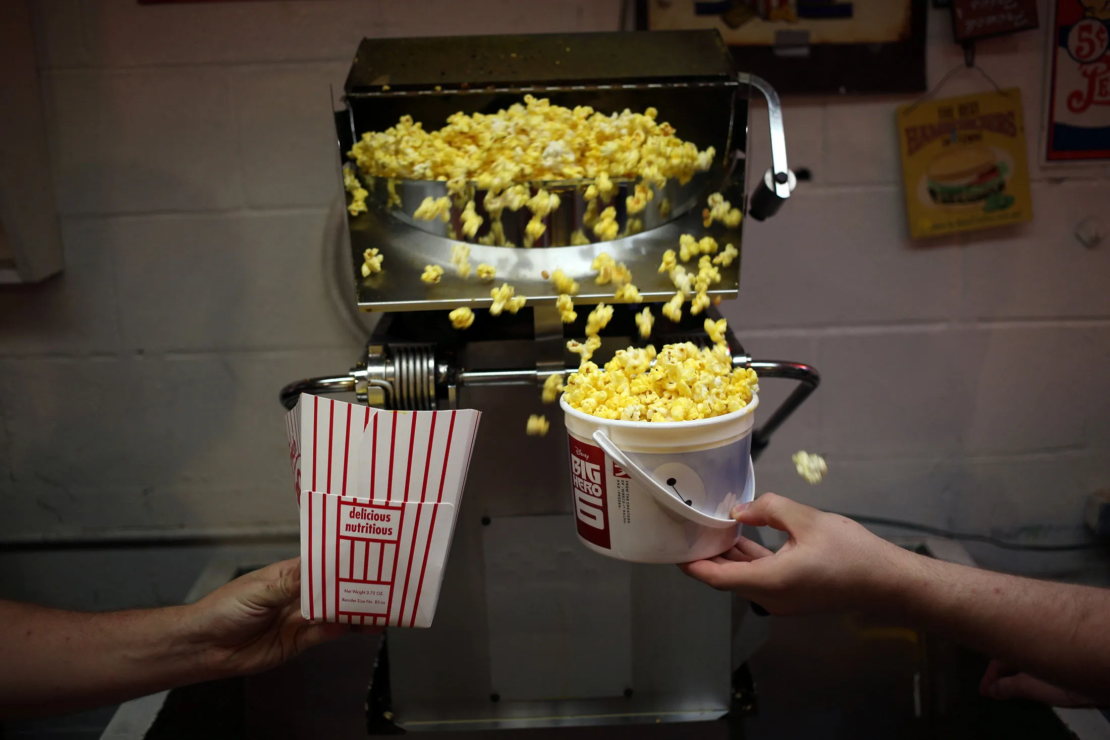 Employees fill popcorn cartons with fresh popcorn inside the snack bar at the Georgetown Drive-In movie theater in Georgetown, Indiana, U.S., on Friday, July 17, 2015. The Georgetown Drive-In opened in 1951 and has been family-owned and operated for the past fifty years.
