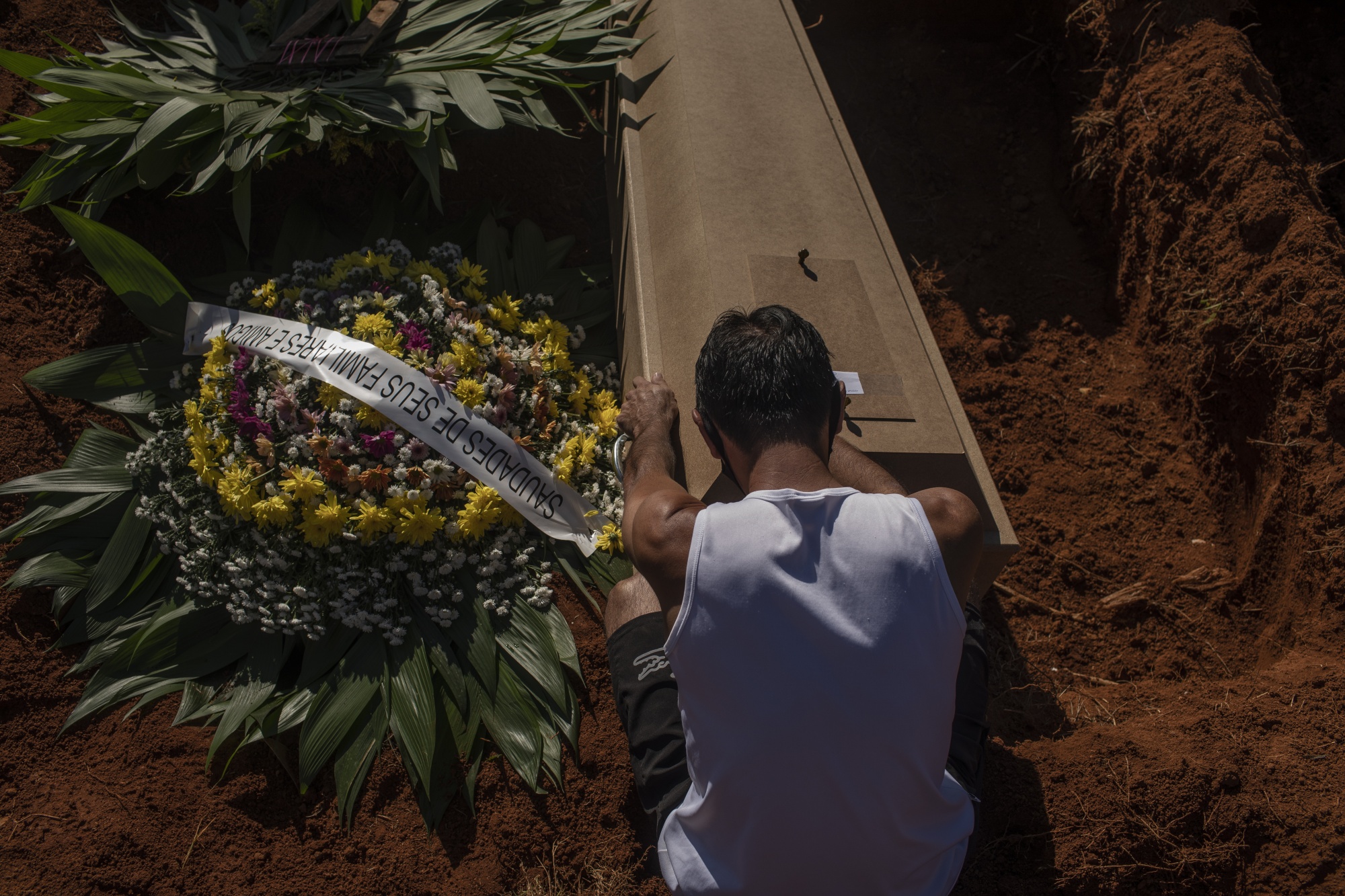 Um enlutado está sentado ao lado do caixão de uma vítima de Covid-19 no Cemitério Vila Formosa em São Paulo, Brasil, em 24 de março.