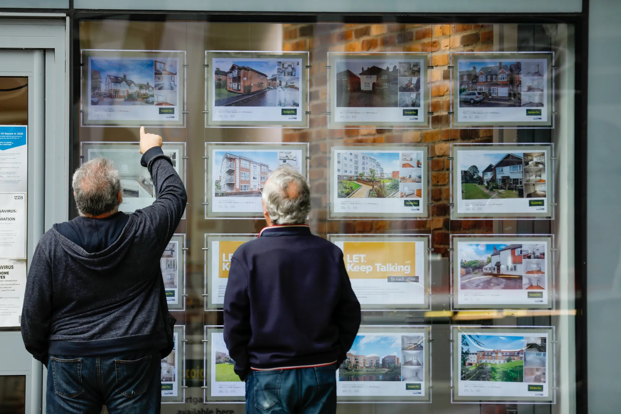 Pedestrians view displays in an estate agent's window in Guildford, U.K.