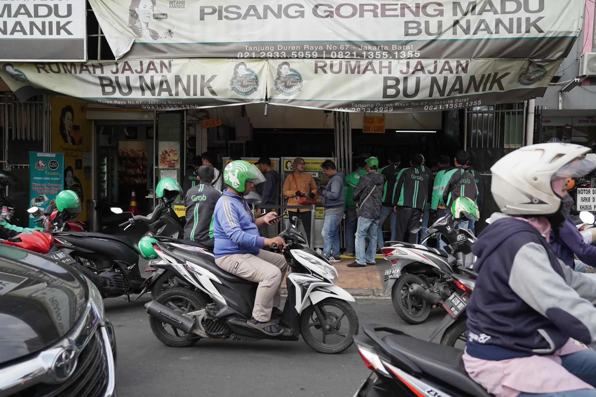 Customers and drivers for Grab Holdings Inc.'s GrabFood collect orders n Jakarta.