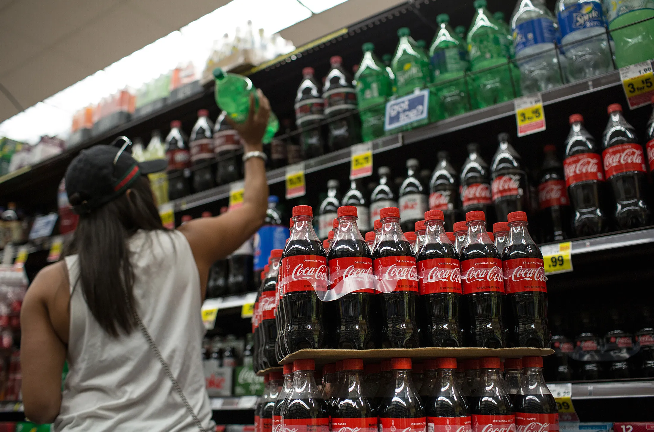 A customer shops as bottles of Coca-Cola Co. brand soda sit on display for sale inside of a Ralphs Grocery Co. in Los Angeles, California, U.S., on Friday, Oct. 20, 2017. Coca-Cola Co. is scheduled to release earnings figures on October 25.
