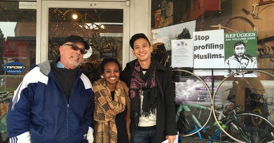 Three canvassers in front of a bike store in Durham, where the anti-discrimination posters are on display.