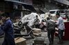 A person uses a smartphone, center, as workers move boxes at a street market in Chongqing, China.