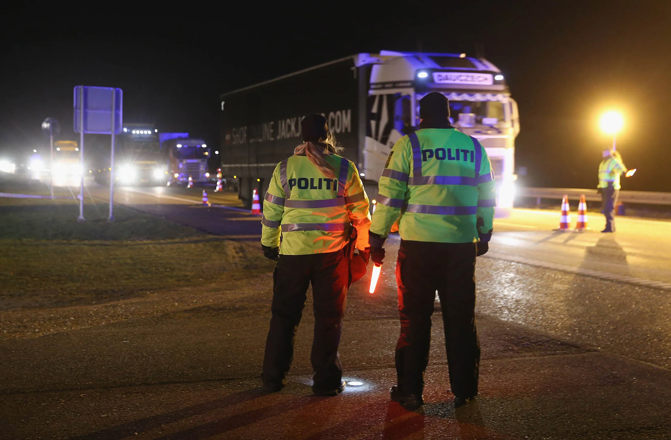 Danish police conducting spot checks on incoming traffic watch a truck pass through from Germany into Denmark at the A7 highway border crossing on January 5, 2016 near Padborg, Denmark. Denmark on Monday introduced temporary spot checks on its southern border with Germany, 12 hours after systematic ID controls on visitors from abroad came into force in neighboring Sweden.
