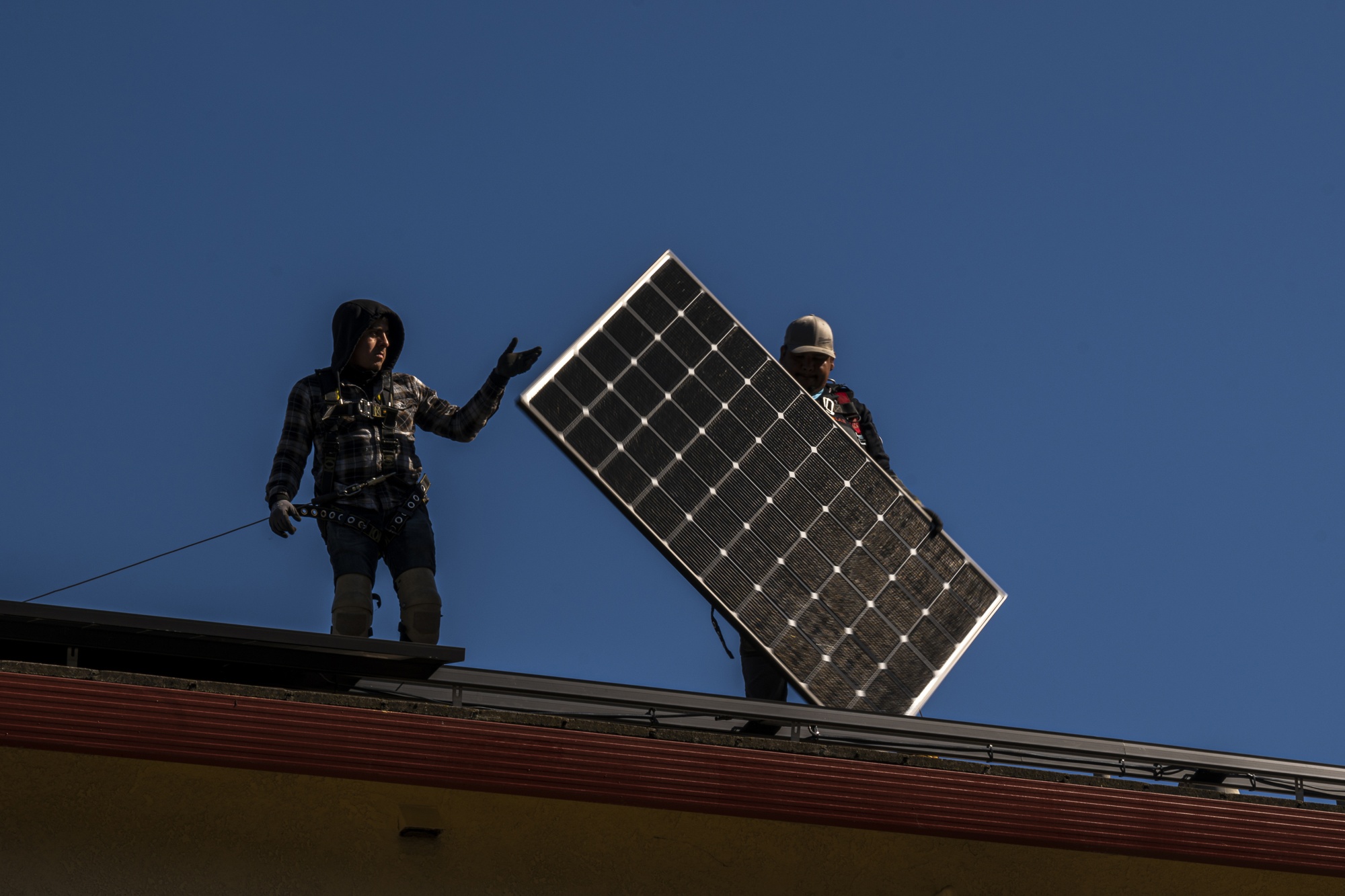 Contractors install solar panels on a home in Hayward, California.