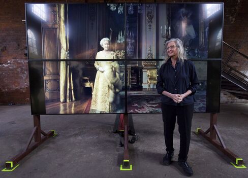 Leibovitz poses in front of a photograph of Britain's Queen Elizabeth II during the exhibition opening.