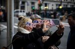 People wearing 2020-themed glasses smile for a 'selfie' photograph near the New York Stock Exchange (NYSE) in New York, U.S., on Tuesday, Dec. 31, 2019.