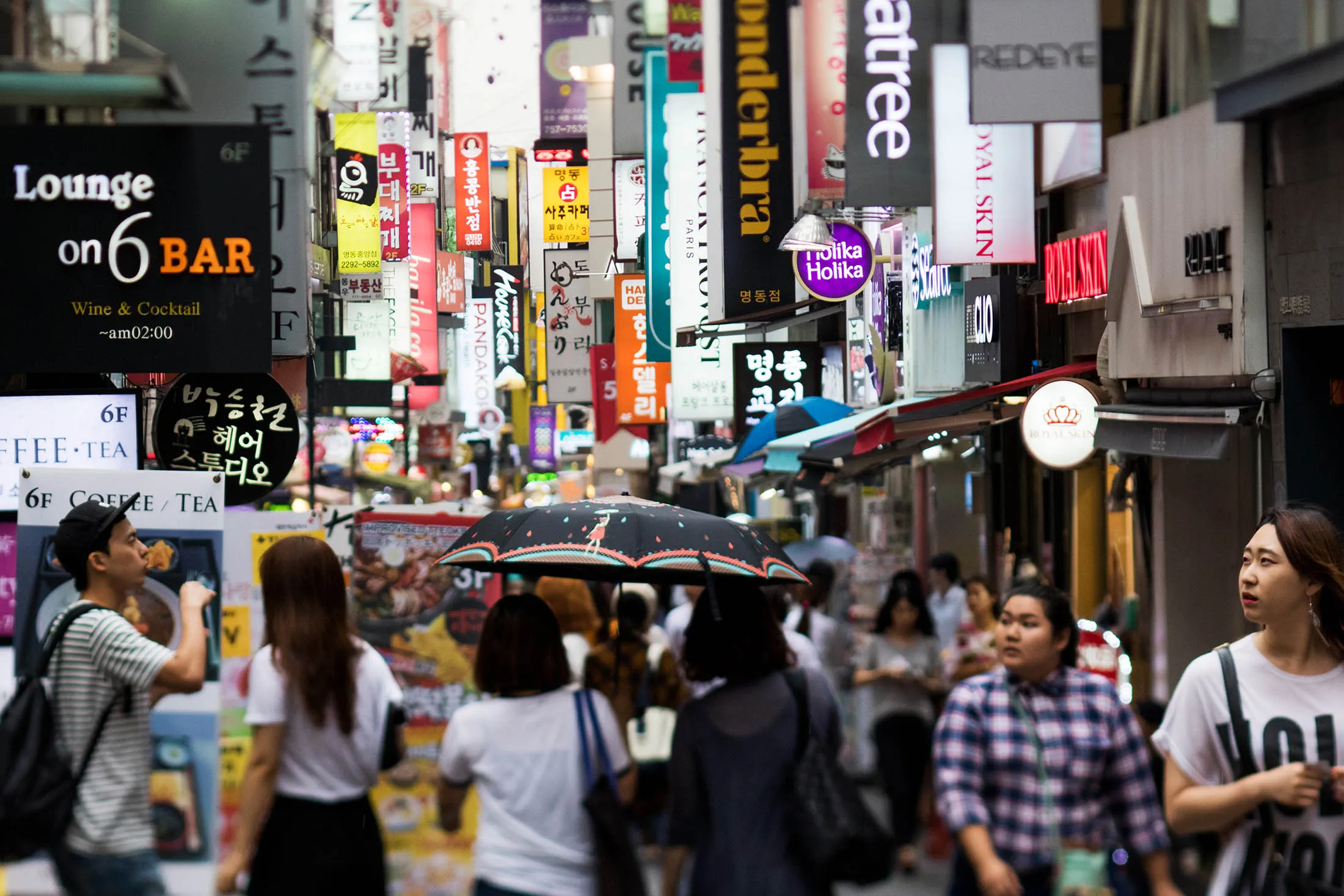 Shoppers and pedestrians walk past stores in the Myeongdong shopping district in Seoul.

