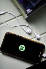 The logo for Spotify is displayed on a smartphone