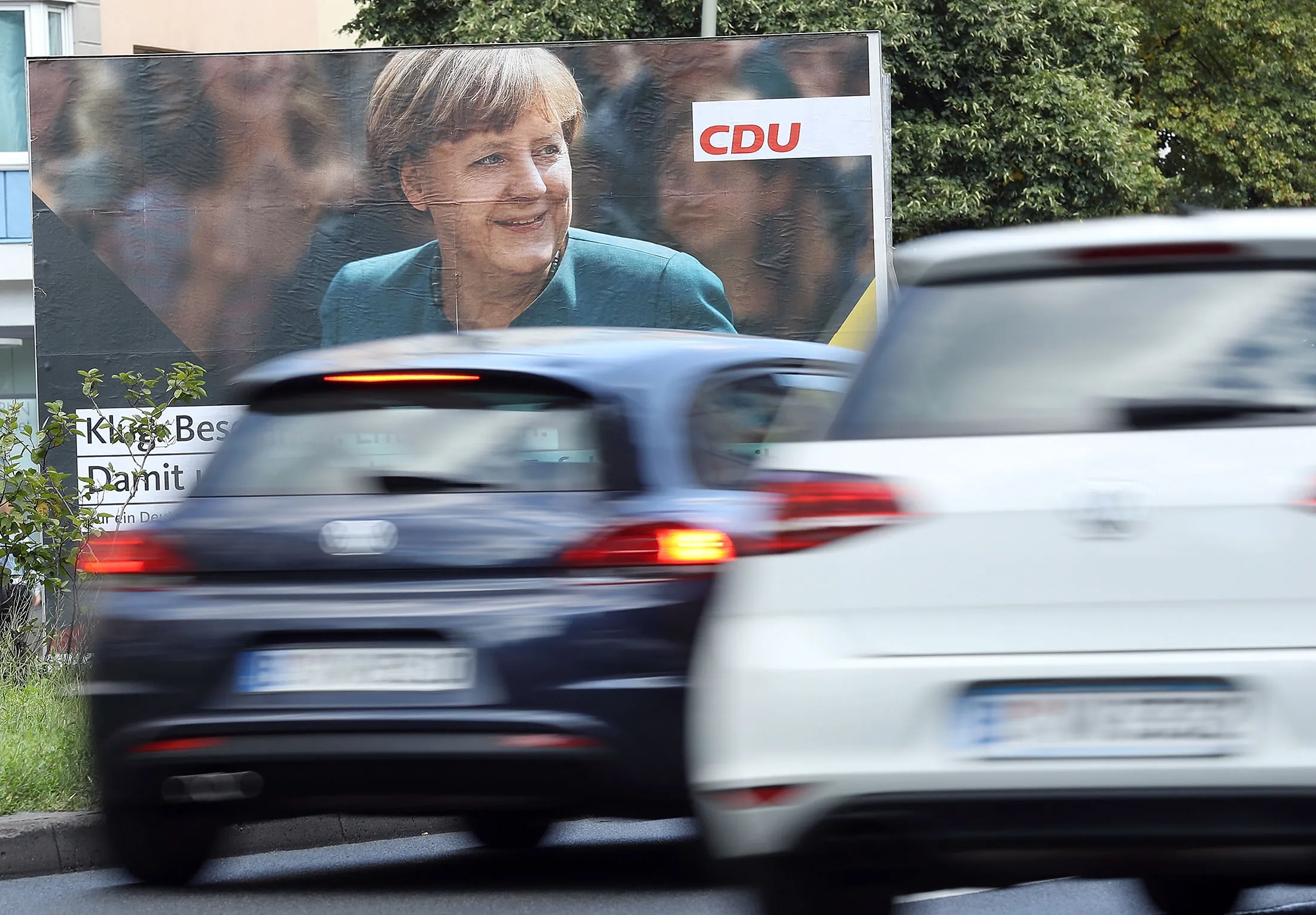 Cars drive past a campaign billboard for Chancellor Angela Merkel in 2017. She is preparing to leave office after 16 years steering the German government.