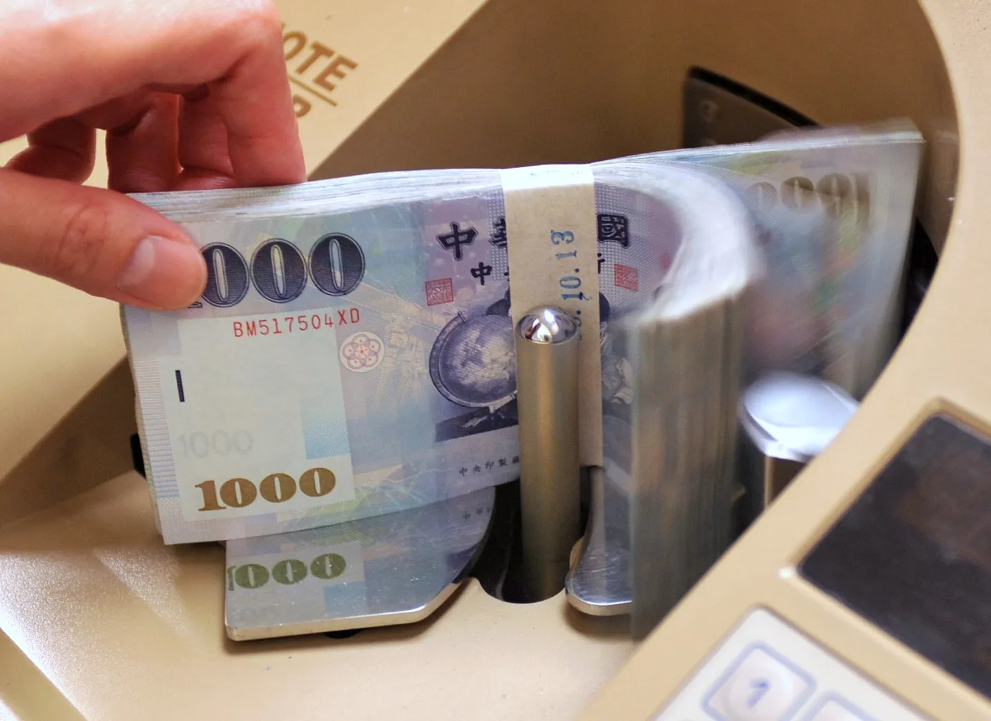 A clerk counts Taiwan 1000 dollar notes