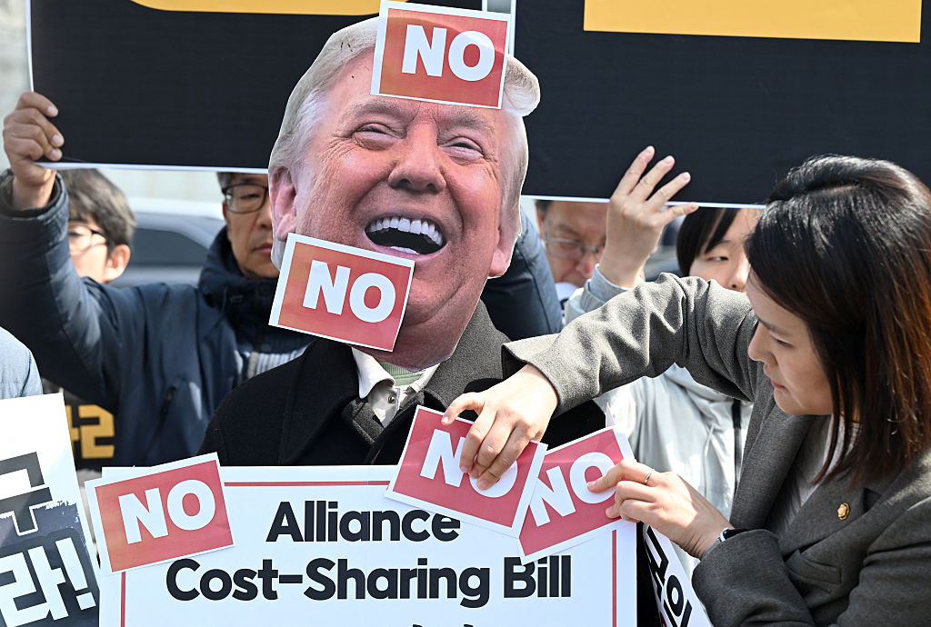 A South Korean protester wears a mask of US President Donald Trump during a protest against Trump's request to dispatch warships to the Strait of Hormuz in front of the US embassy in Seoul on March 16, 2026. South Korea said on March 15 it was paying close attention to US President Donald Trump's call for Seoul and other countries to send warships to help protect oil supplies passing through the Strait of Hormuz. (Photo by Jung Yeon-je / AFP via Getty Images) Photographer: JUNG YEON-JE/AFP