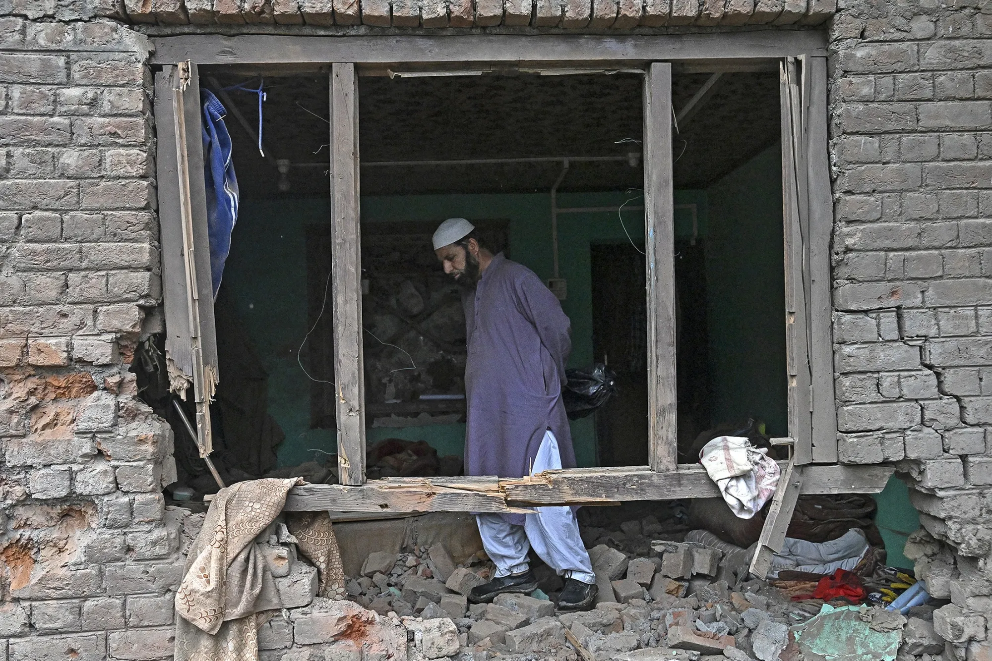 A local resident inspects his house that was damaged by artillery shelling in Uri, India, on May 9.
