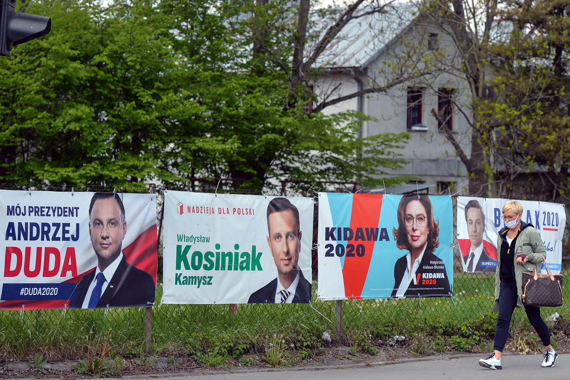 A pedestrian walks by election banners outside Krakow.