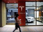 A pedestrian walks past a closed Tesla Inc. store.