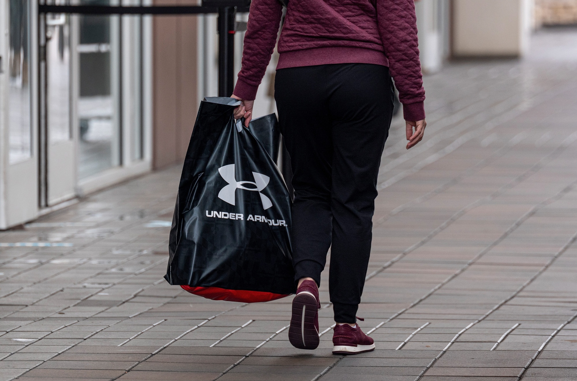 A shopper carries an Under Armour bag.