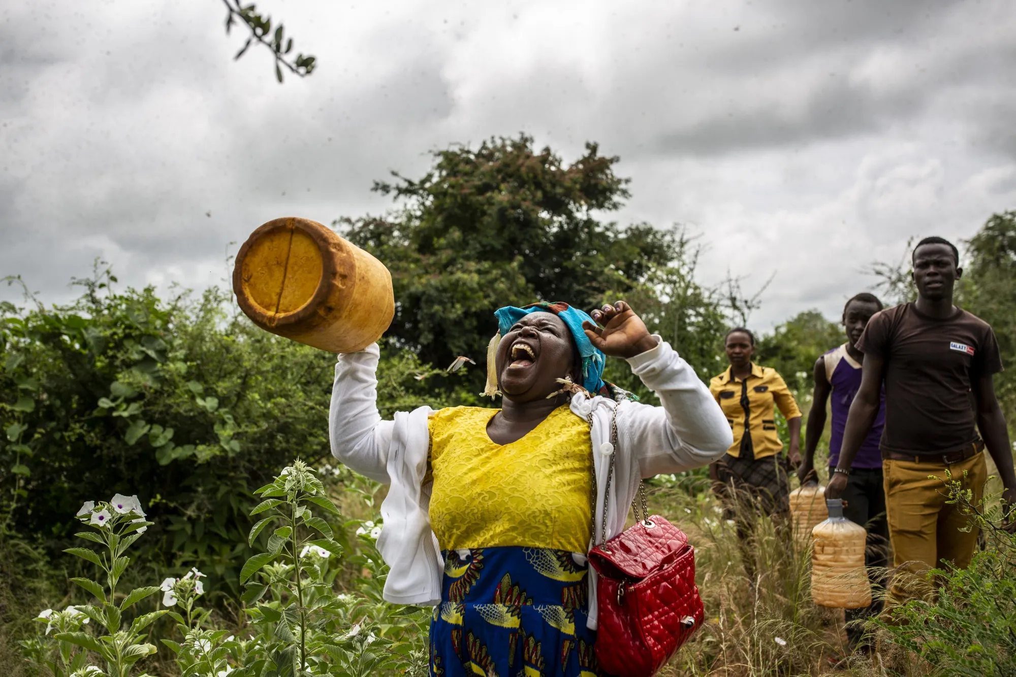 A local resident shakes a bottle filled with pebbles at a swarm of desert locusts in Mathiakani, Kitui County, Kenya.