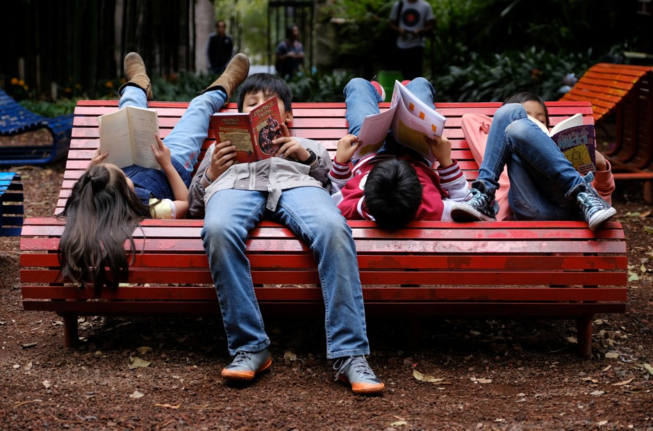 Children read books on a park bench in Mexico City.