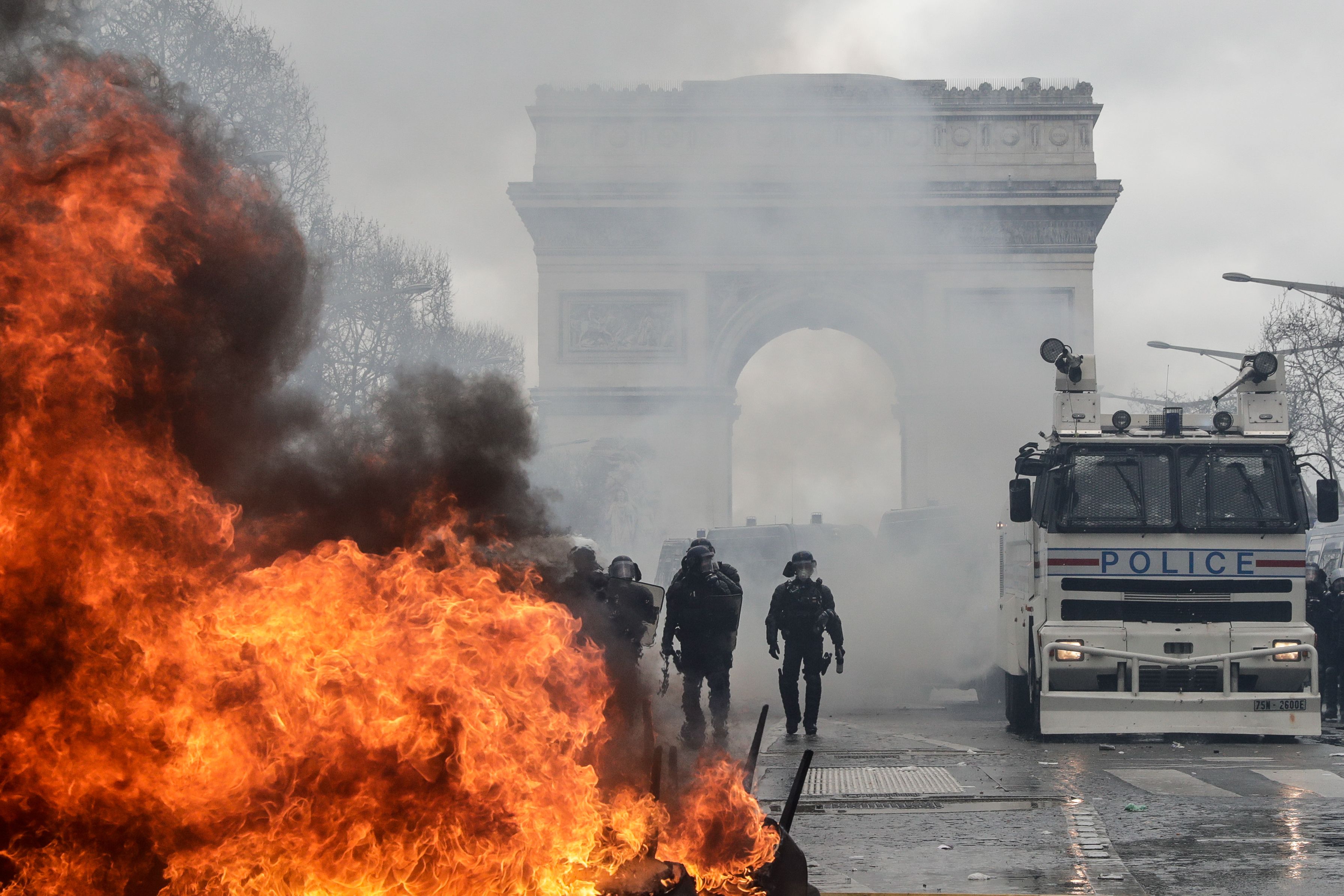French riot police forces stand behind a burning barricade on the Champs-Elysees on March 16.