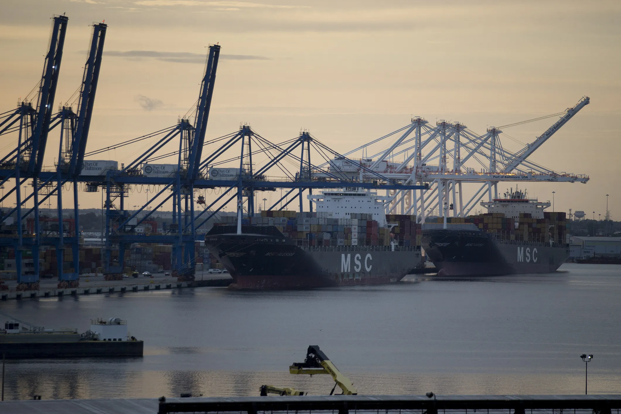 Cargo vessels berthed at the Port of Baltimore next to gantry and super post-Panamex cranes.