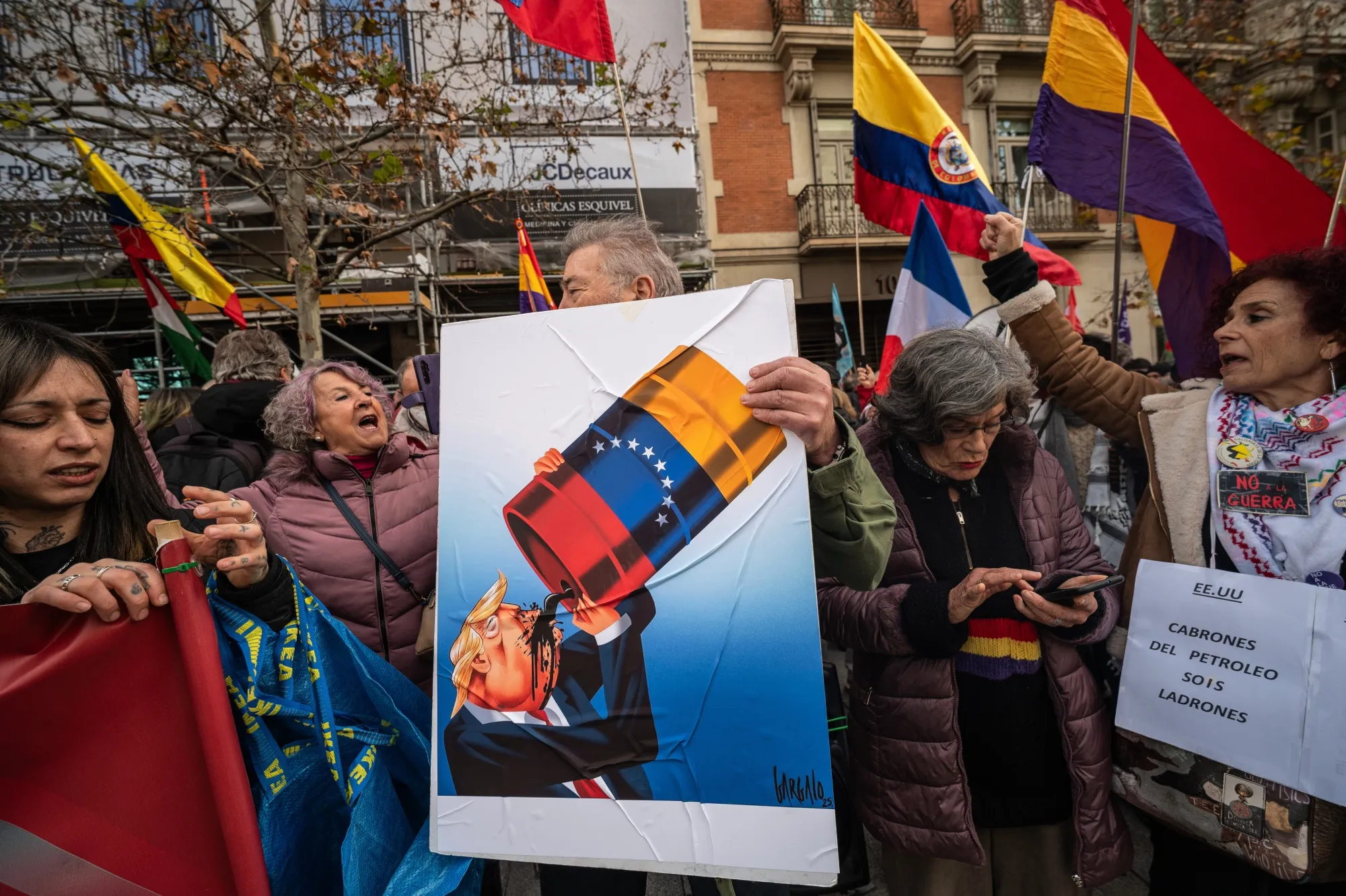 A man holds a placard during a protest showing US President Donald Trump drinking from a barrel of oil outside the US Embassy of Madrid on Jan. 4.