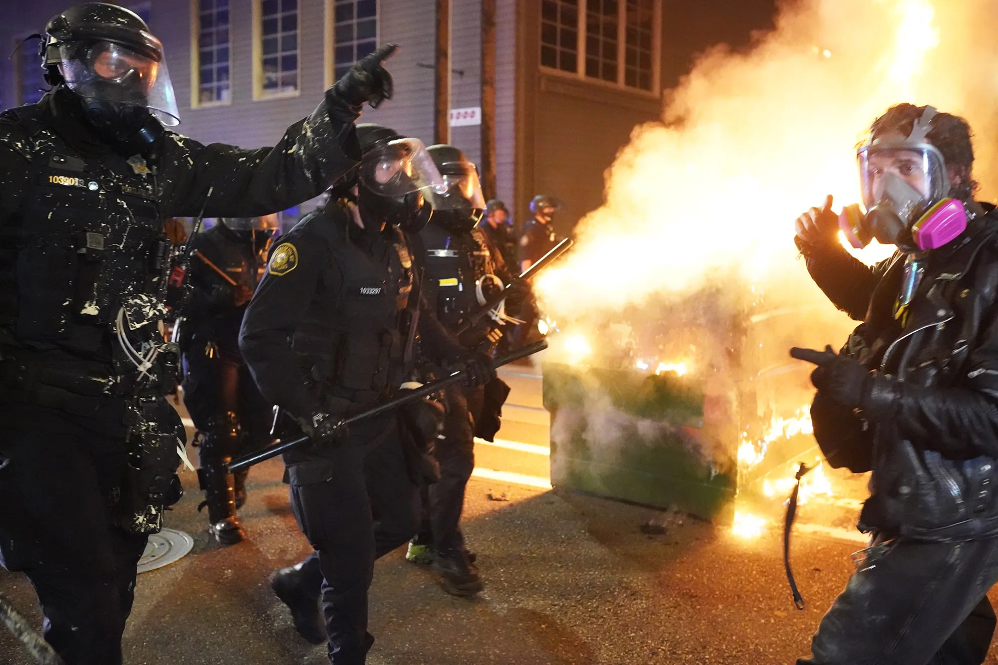 Portland police officers push protesters past a dumpster fire&nbsp;in the early morning on Aug.&nbsp;21.
