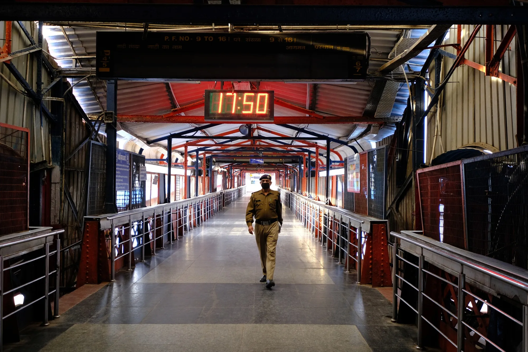 A police officer wearing a protective mask walks inside the empty Delhi Junction railway station on March 30.