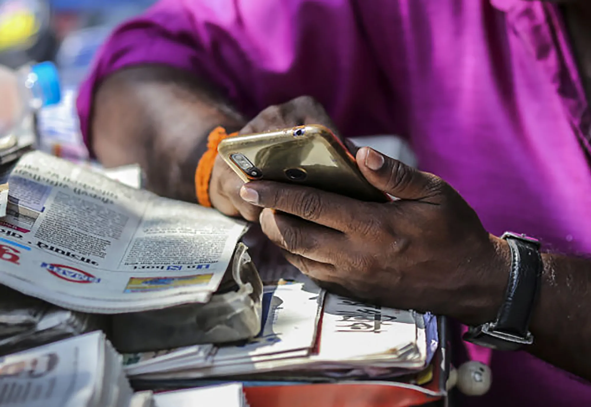 A vendor uses a smartphone while waiting for customers at a newspaper stand in Mumbai.&nbsp;