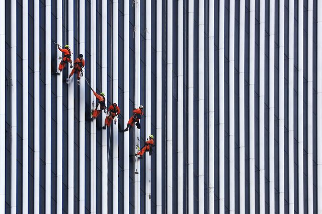 In Singapore, Migrants suspended from cables perform work on a building construction site on June 4.