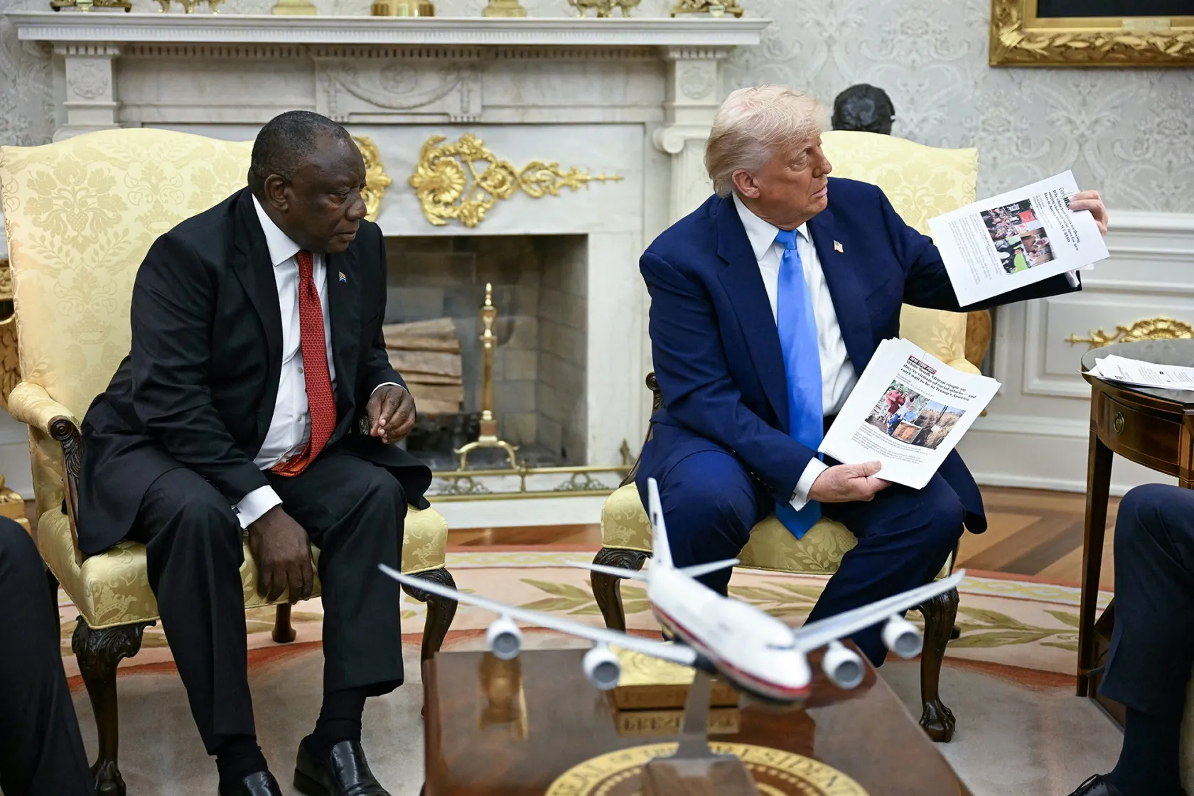 Donald Trump shows pictures as he meets with&nbsp;Cyril Ramaphosa in the Oval Office of the White House in Washington, DC, on May 21.