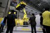 A Fanuc Corp. industrial robot lifts a vehicle at the International Robot Exhibition in Tokyo, Japan, on Wednesday, Nov. 29, 2017. The expo runs through Dec. 2.