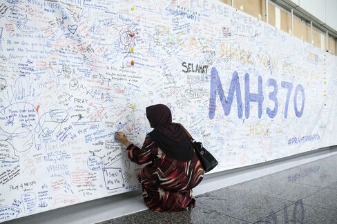 A woman writes a message on a banner for missing Malaysian Airline System Bhd. (MAS) flight MH370 at Kuala Lumpur International Airport (KLIA) in Sepang, Malaysia, on March 14, 2014.