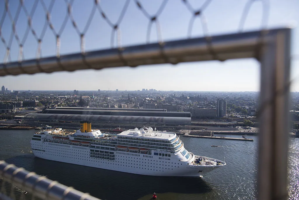 A cruise ship passes Amsterdam central railway station.