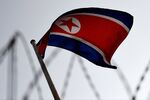 The North Korean flag is seen flying in backdrop of barbed wire.
