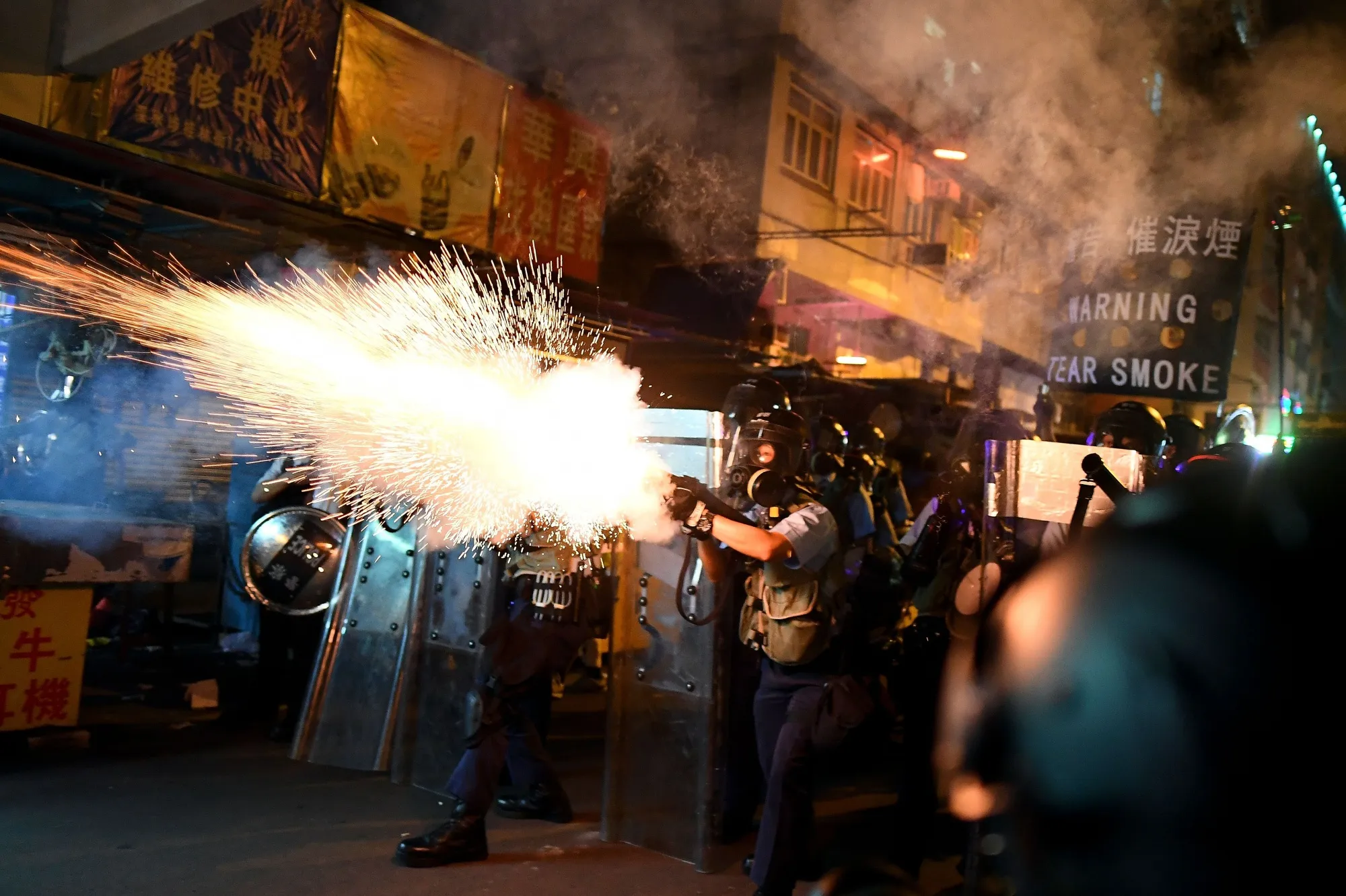 Police personnel fire tear-gas shells to disperse protesters in Sham Shui Po on Aug. 14.