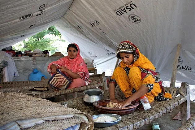 Displaced women cook in a USAID makeshift tent near Muzaffargarh, Pakistan after floods caused $7 billion in damage