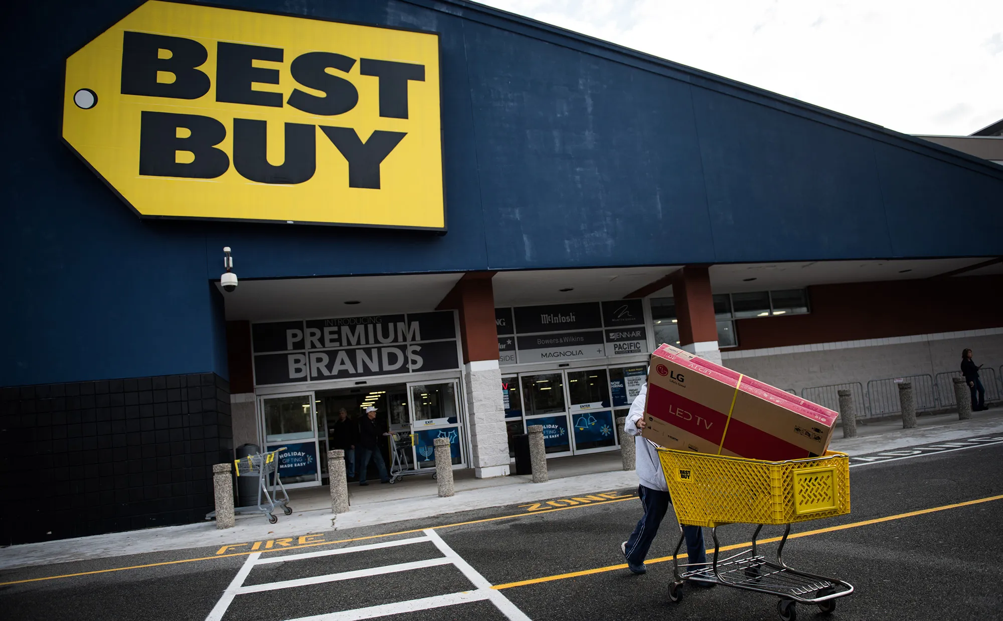 A customer pushes an LG Electronics Inc. television box in a shopping cart outside a Best Buy store.