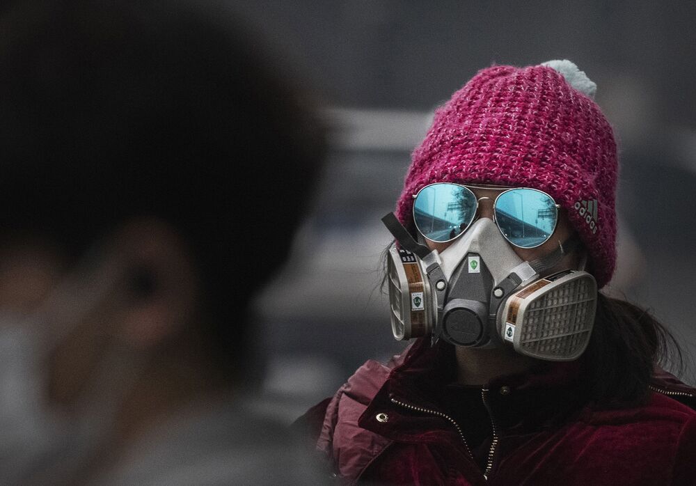 A Chinese woman wears a protective mask as she waits for a bus at a usually busy stop in Beijing, on Feb. 13.