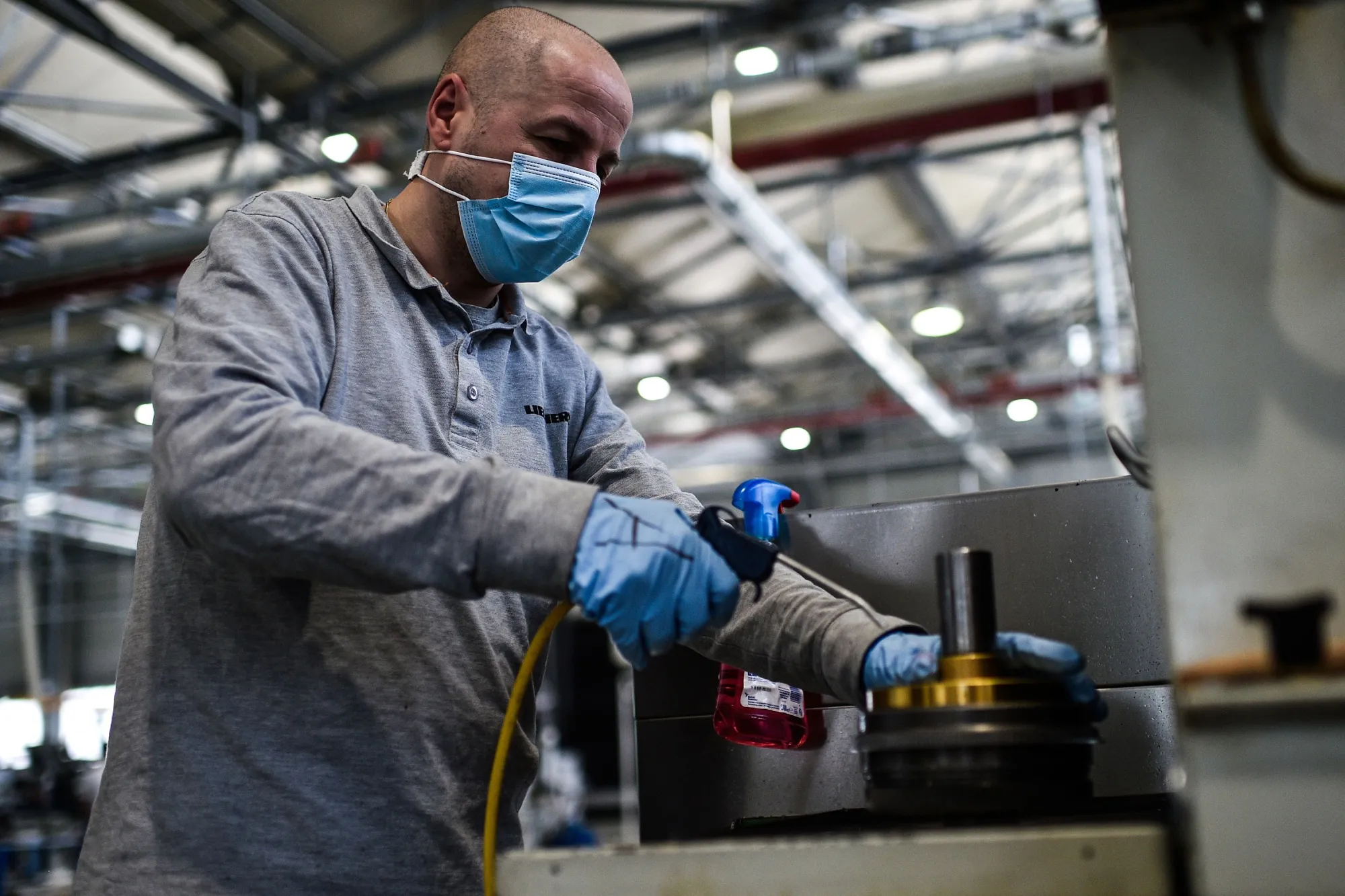 An employee wearing a face mask and gloves works at the&nbsp;Liebherr factory in Collegno near Turin, on May 5.