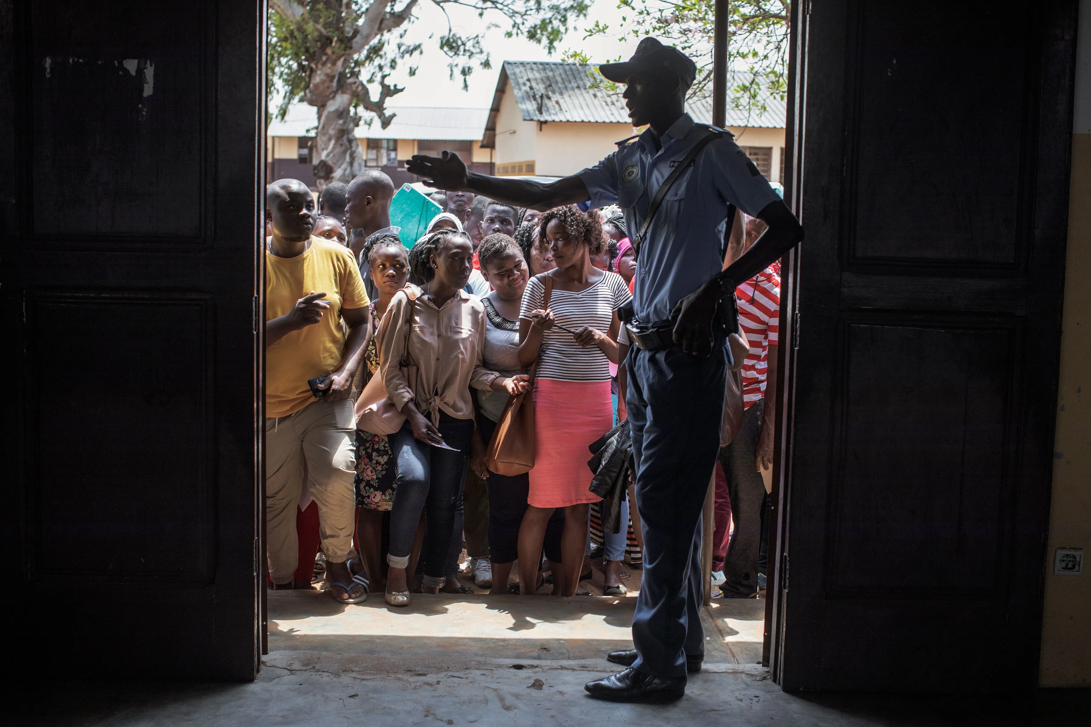 People wait in outside a school classroom to register their details on the eve of elections, Oct. 14.