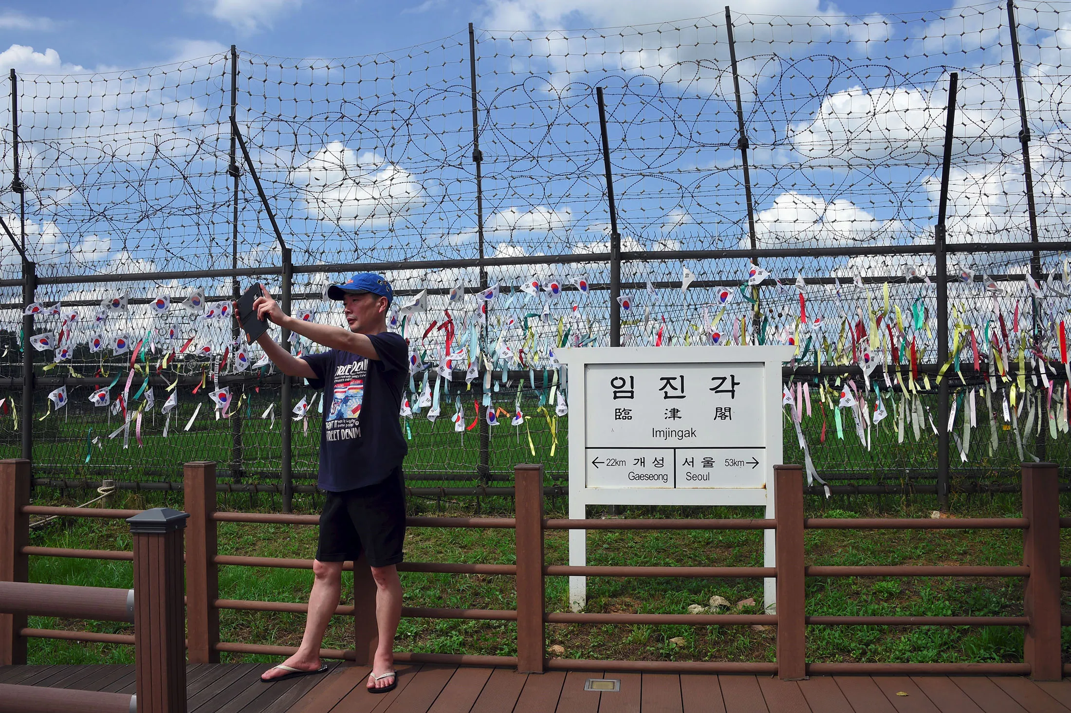 A man takes a selfie in front of a sign board showing the distance to Gaeseong&nbsp;near the DMZ.