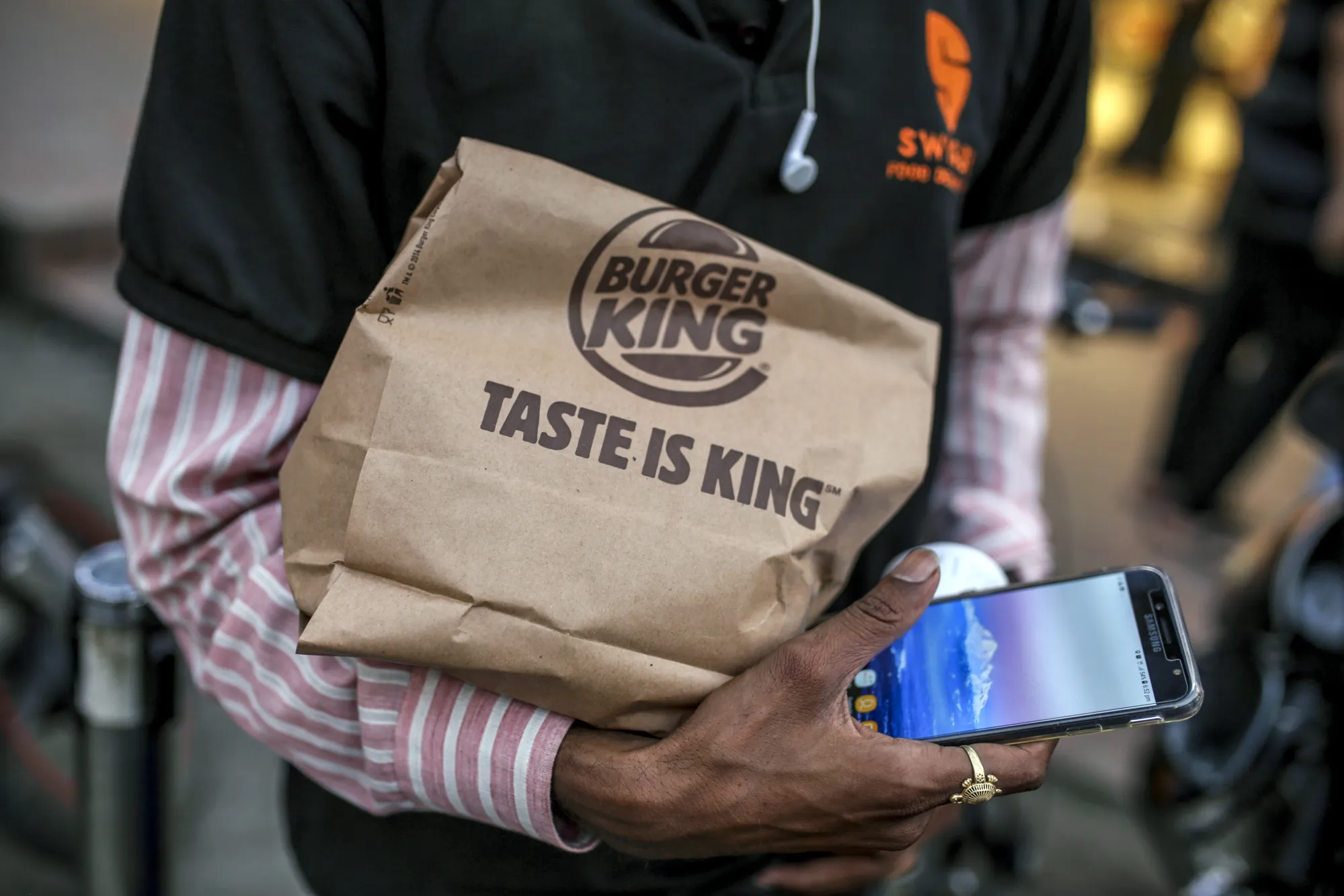 A courier of Swiggy&nbsp;holds take-out food from a Burger King restaurant&nbsp;in Mumbai.