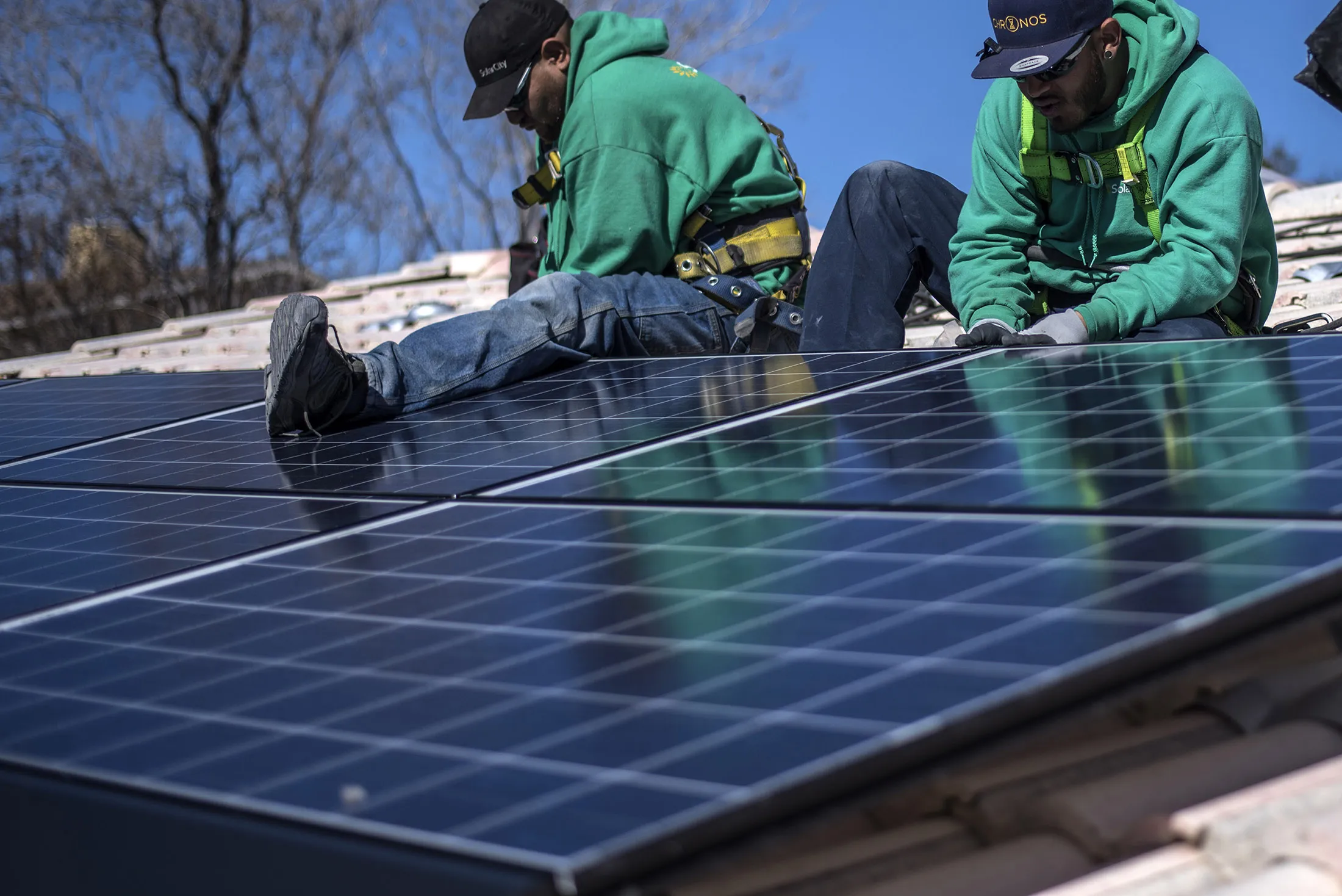 Workers secure solar panels to a rooftop during a SolarCity Corp. residential installation in Albuquerque, New Mexico.
