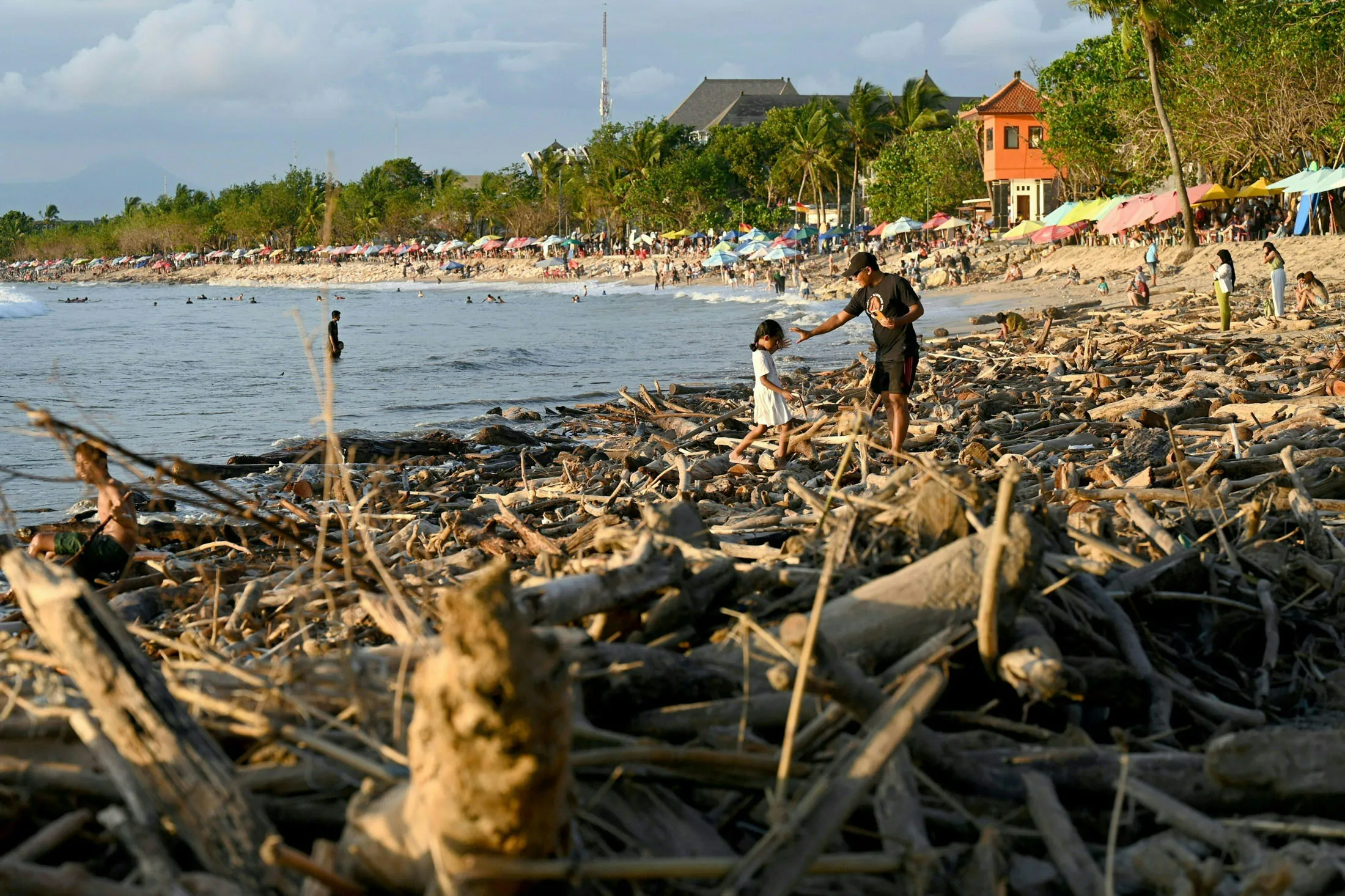 Visitors among the debris and rubbish washed ashore at Bali’s&nbsp;Kuta Beach.