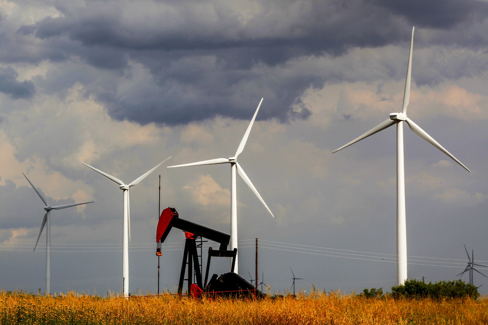 A pumpjack in front of wind turbines in West Texas.
