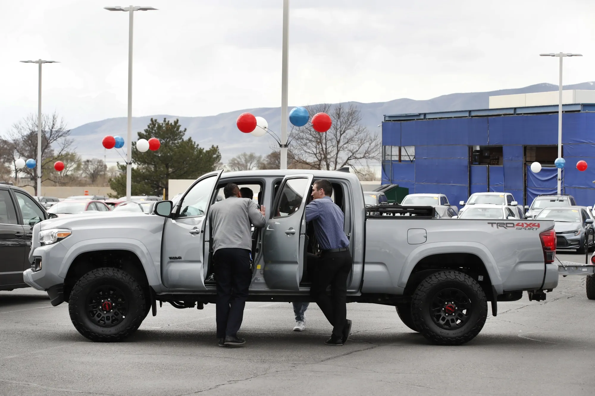 A salesman shows customers a Toyota Tacoma pickup truck.